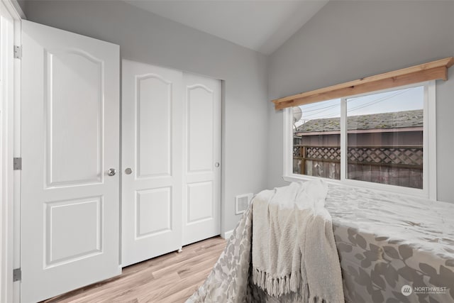 bedroom with a closet, light hardwood / wood-style floors, and vaulted ceiling