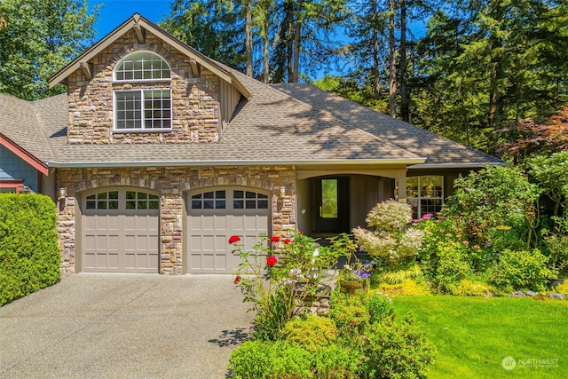 view of front of house with driveway, stone siding, a shingled roof, and a front yard