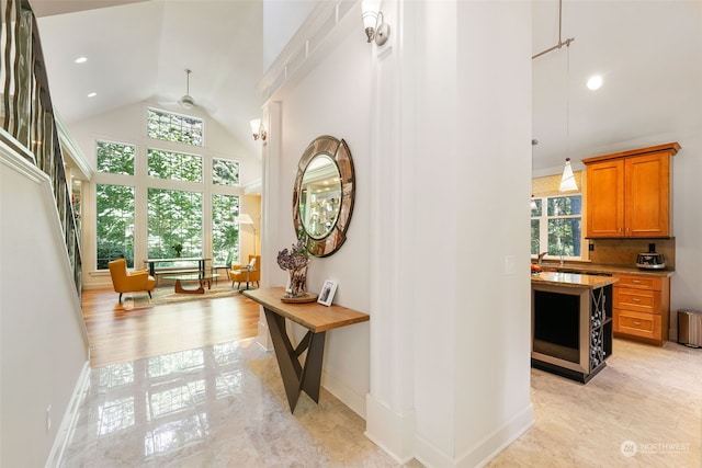 hallway with baseboards, high vaulted ceiling, a wealth of natural light, and recessed lighting