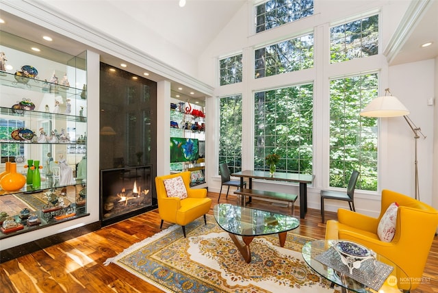 sitting room with high vaulted ceiling, recessed lighting, a large fireplace, and wood finished floors