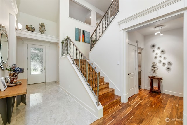 foyer entrance with stairs, baseboards, and wood finished floors