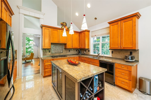 kitchen featuring black appliances, light stone counters, brown cabinetry, and a sink