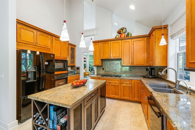 kitchen featuring light stone counters, a sink, brown cabinets, black appliances, and tasteful backsplash