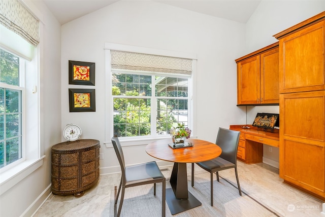 dining area featuring lofted ceiling, plenty of natural light, and built in desk