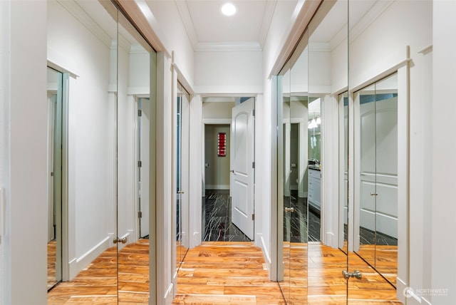 hallway with light wood-type flooring and ornamental molding