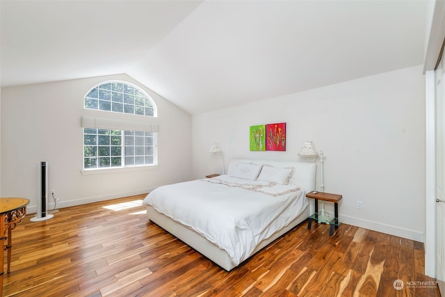 bedroom with vaulted ceiling, wood finished floors, and baseboards