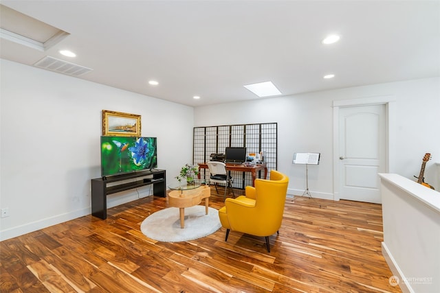 living area with baseboards, visible vents, wood finished floors, and recessed lighting