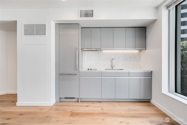 interior space with sink, decorative backsplash, a healthy amount of sunlight, and light wood-type flooring