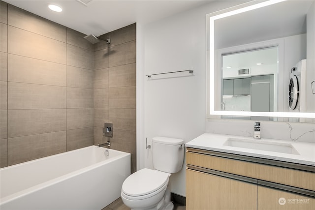 full bathroom featuring vanity, washer / dryer, toilet, and tiled shower / bath combo