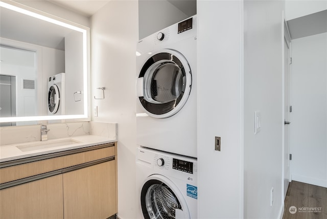 washroom featuring dark hardwood / wood-style floors, stacked washing maching and dryer, and sink