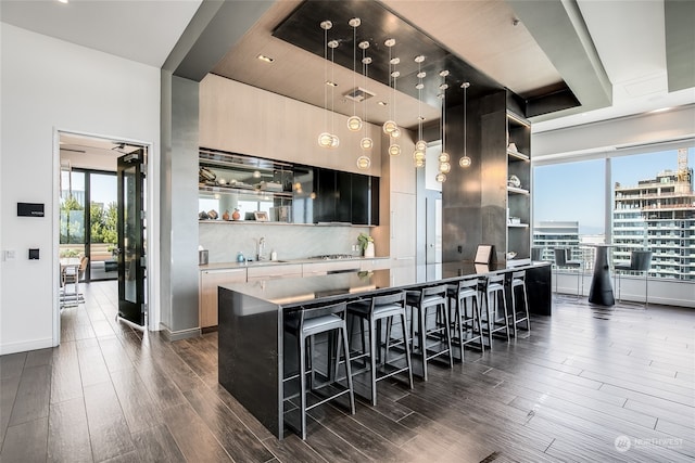 kitchen with pendant lighting, sink, a kitchen bar, dark hardwood / wood-style floors, and a kitchen island