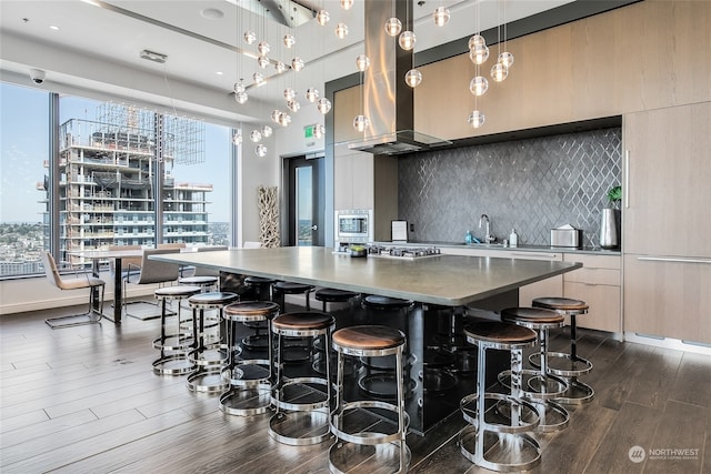 kitchen featuring dark hardwood / wood-style floors, island exhaust hood, decorative light fixtures, and backsplash