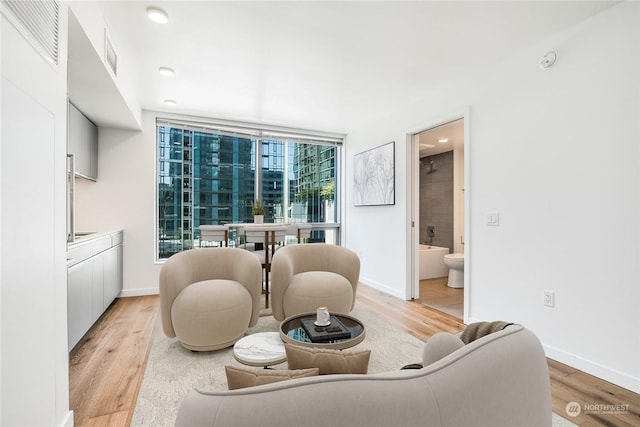 living room with a wall of windows and light hardwood / wood-style floors