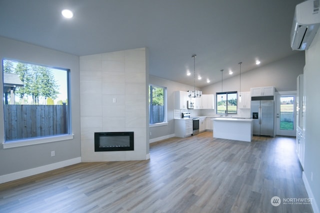 kitchen featuring a wall mounted air conditioner, decorative light fixtures, white cabinetry, a center island, and stainless steel appliances