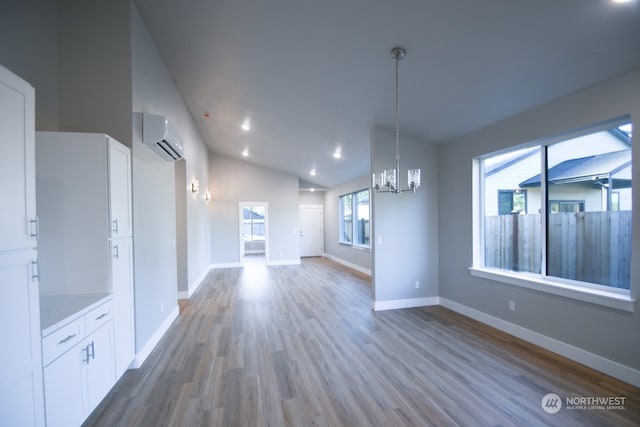 unfurnished living room featuring lofted ceiling, a wall mounted air conditioner, hardwood / wood-style floors, and a chandelier