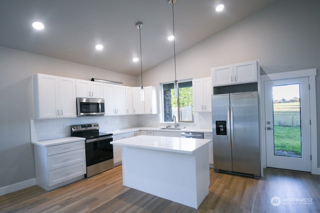 kitchen featuring appliances with stainless steel finishes, hanging light fixtures, white cabinets, a kitchen island, and dark hardwood / wood-style flooring