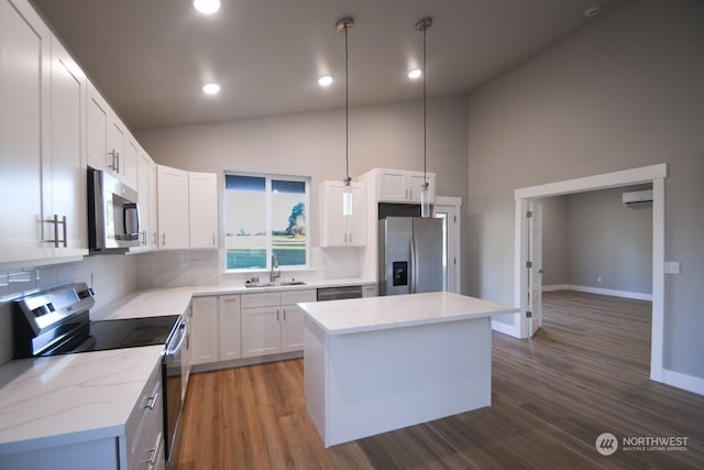 kitchen featuring appliances with stainless steel finishes, a center island, white cabinets, and backsplash