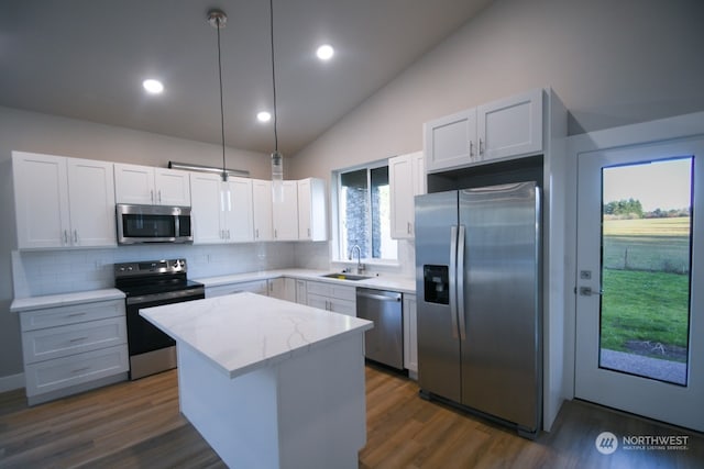 kitchen with sink, a center island, pendant lighting, stainless steel appliances, and white cabinets