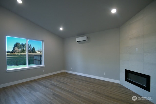 unfurnished living room with lofted ceiling, wood-type flooring, a tiled fireplace, and an AC wall unit