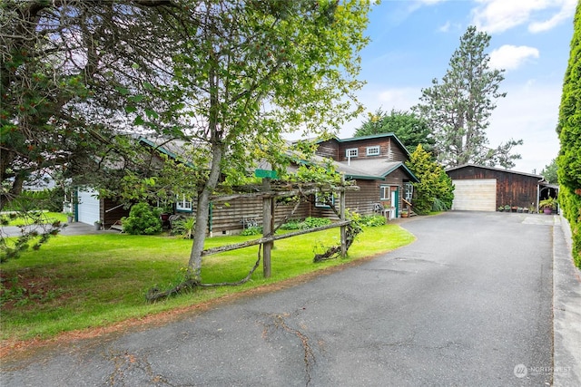 view of front of home featuring a garage, an outbuilding, and a front yard