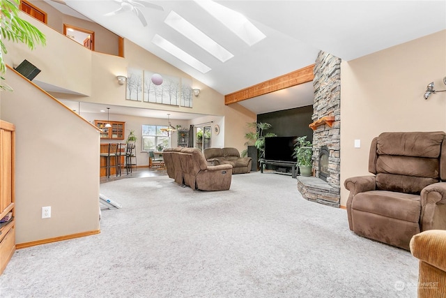 carpeted living room featuring high vaulted ceiling, a skylight, and ceiling fan with notable chandelier