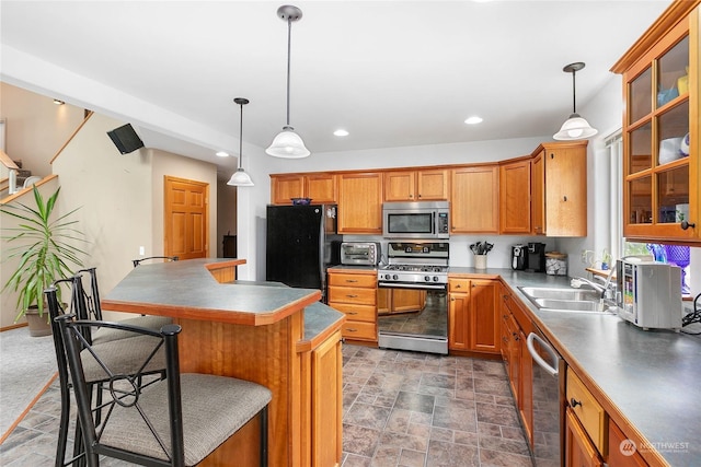 kitchen with sink, hanging light fixtures, stainless steel appliances, a kitchen breakfast bar, and a kitchen island