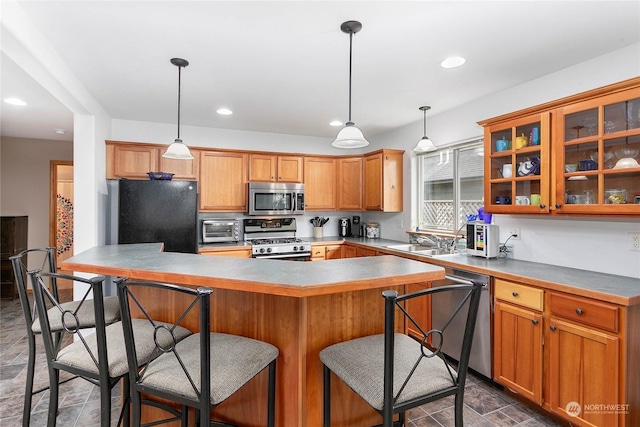 kitchen with sink, decorative light fixtures, a kitchen bar, and appliances with stainless steel finishes