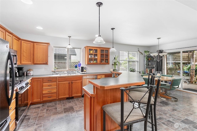 kitchen featuring pendant lighting, stainless steel appliances, a center island, a notable chandelier, and a kitchen bar