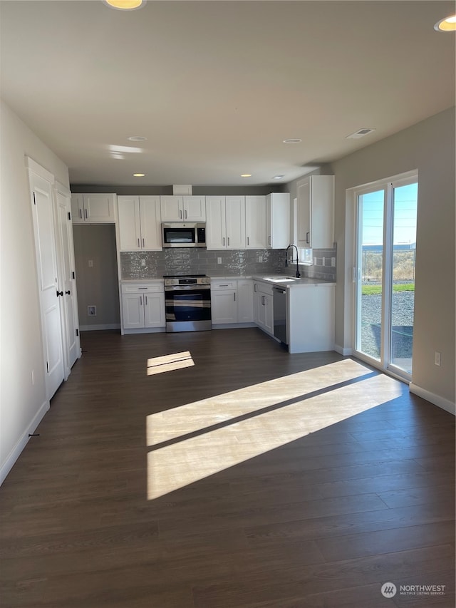 kitchen with white cabinetry, sink, dark wood-type flooring, tasteful backsplash, and appliances with stainless steel finishes