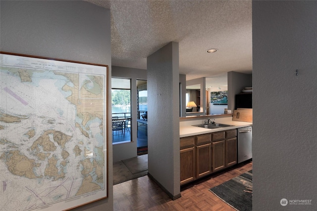 kitchen featuring sink, dark parquet flooring, a textured ceiling, and dishwasher