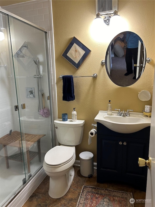 bathroom with a shower with door, vanity, and toilet