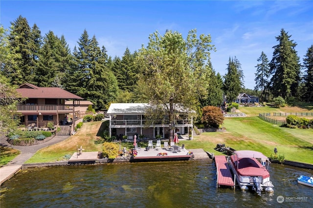 dock area with a water view, boat lift, and a lawn