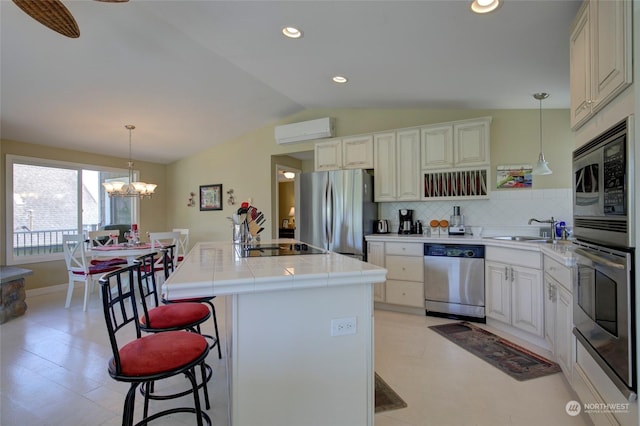 kitchen with appliances with stainless steel finishes, backsplash, a center island with sink, a wall mounted AC, and lofted ceiling