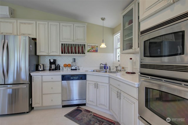 kitchen with appliances with stainless steel finishes, light tile patterned floors, sink, pendant lighting, and vaulted ceiling