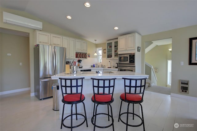 kitchen featuring heating unit, lofted ceiling, appliances with stainless steel finishes, and a wall unit AC