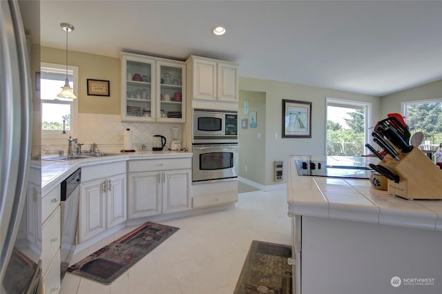 kitchen featuring pendant lighting, sink, backsplash, stainless steel appliances, and tile counters