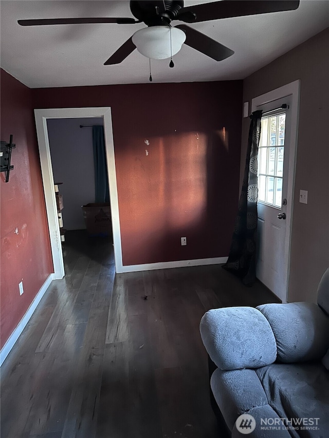 unfurnished living room featuring ceiling fan, baseboards, and wood finished floors