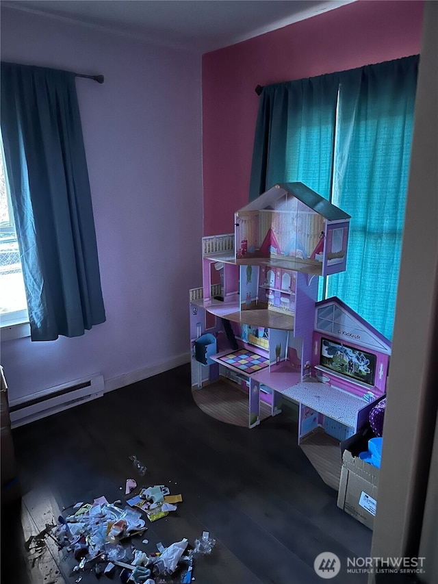 bedroom with baseboards, baseboard heating, and wood finished floors