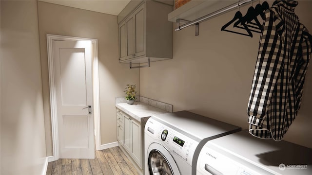 laundry area with washing machine and clothes dryer, cabinets, and light hardwood / wood-style floors