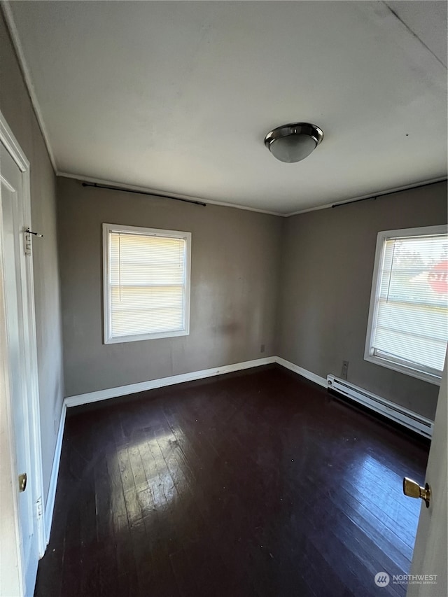 spare room with a baseboard heating unit, wood-type flooring, and a wealth of natural light