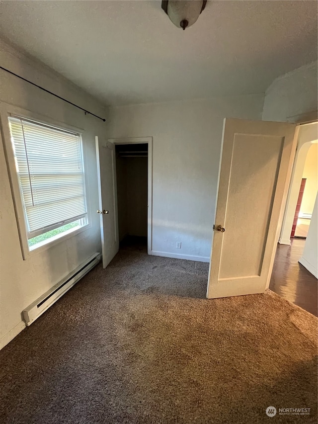 unfurnished bedroom with dark colored carpet and a baseboard radiator