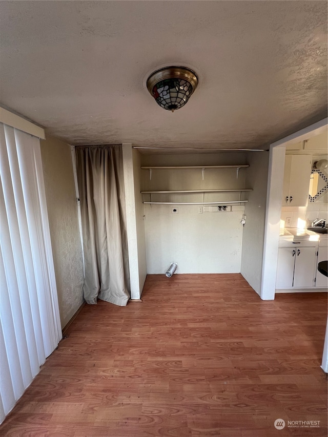 unfurnished dining area with sink, a textured ceiling, and hardwood / wood-style flooring