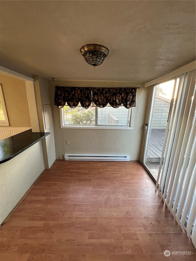 unfurnished dining area featuring a baseboard radiator and wood-type flooring