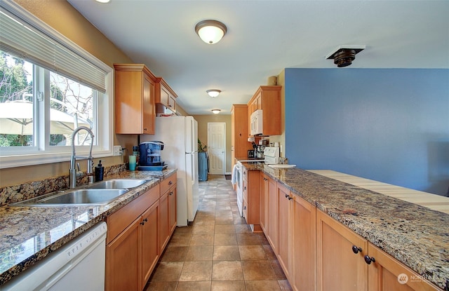 kitchen with light tile patterned flooring, sink, white appliances, and stone countertops