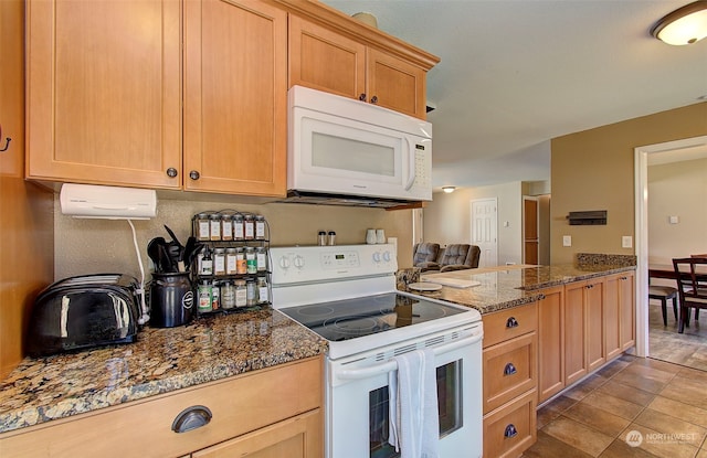 kitchen featuring dark stone counters, light brown cabinetry, white appliances, and light tile patterned floors