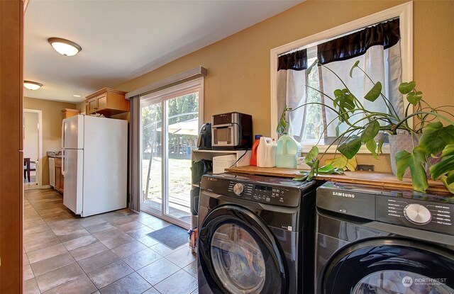 clothes washing area featuring light tile patterned flooring and washer and dryer