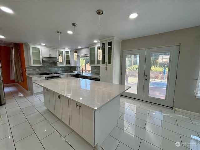 kitchen with white cabinetry, a center island, backsplash, and decorative light fixtures