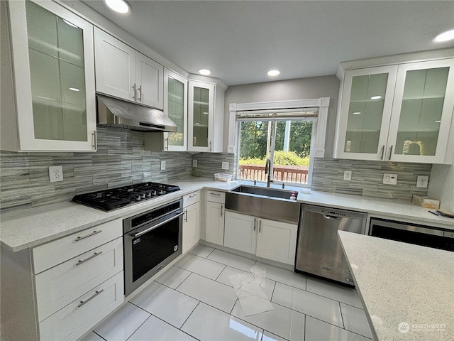 kitchen featuring tasteful backsplash, appliances with stainless steel finishes, light stone counters, and white cabinets