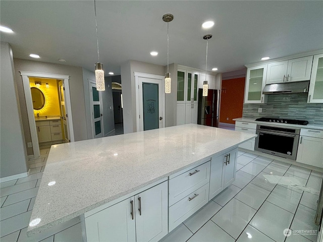 kitchen featuring appliances with stainless steel finishes, decorative light fixtures, white cabinets, backsplash, and light stone countertops