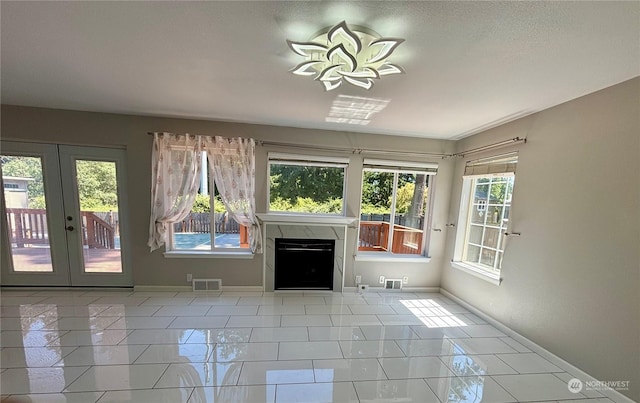 unfurnished living room with light tile patterned floors, a fireplace, and french doors